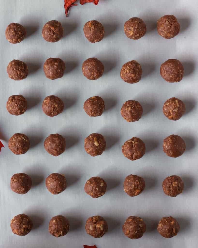 The truffles are shaped into little balls and are lined on a baking sheet with parchment paper.
