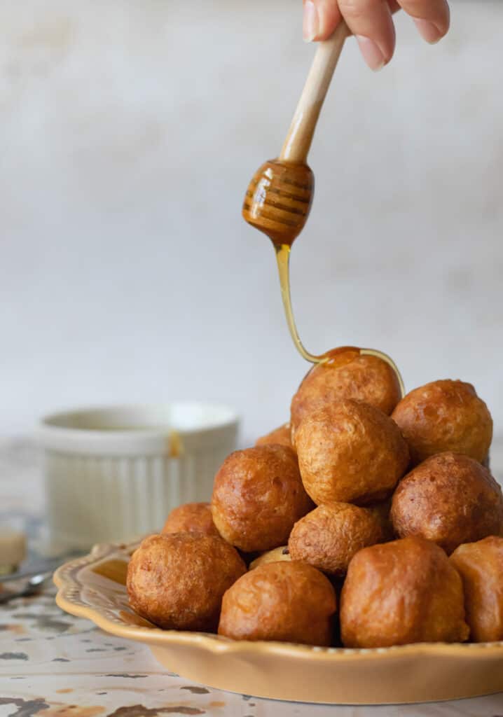 Topping loukoumades with honey.