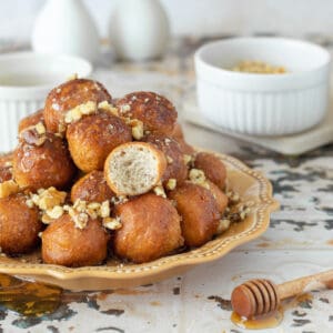 Loukoumades served on a plate with honey, cinnamon and walnuts.