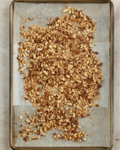 Toasted crushed almonds in a baking sheet lined with parchment paper.