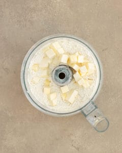 Photo showing the dry ingredients and butter in the food processor.