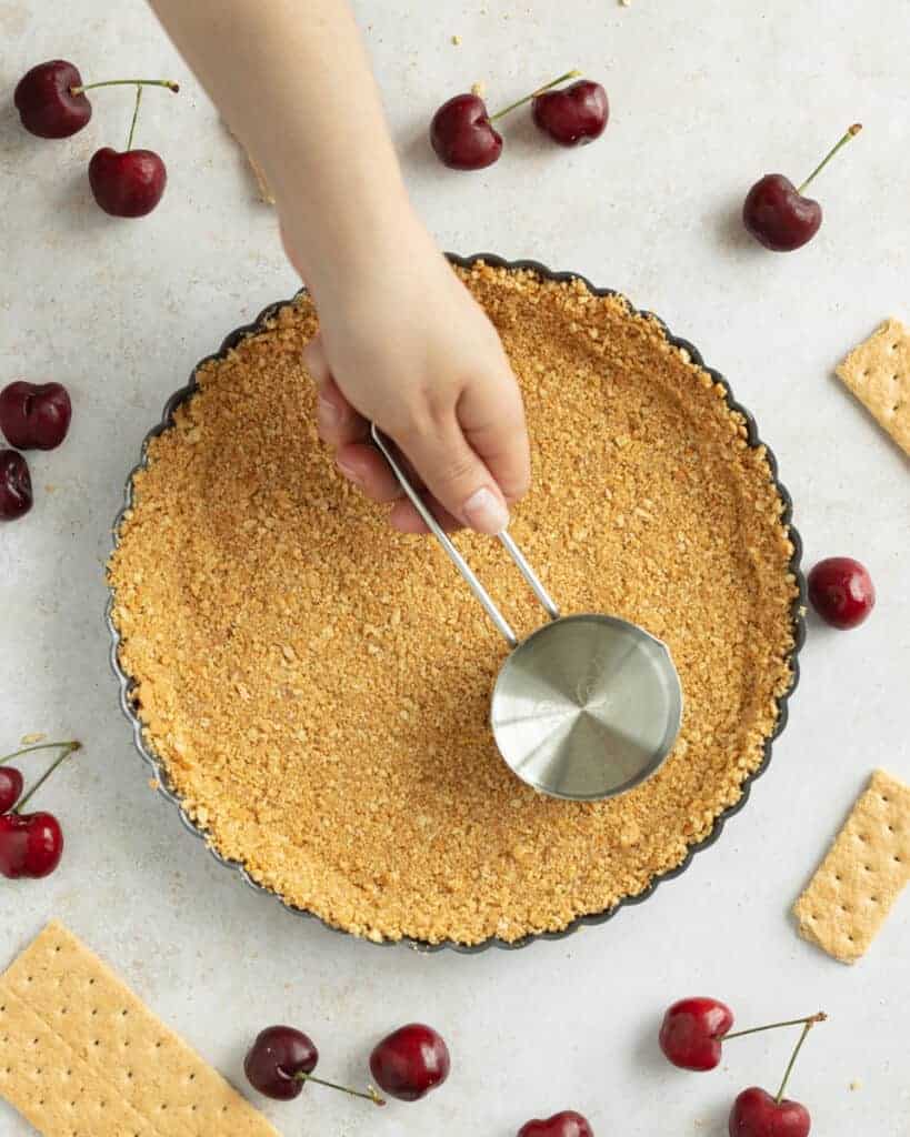 Press the mixture into the bottom of the tart pan and slightly up the sides using the bottom side of a measuring cup