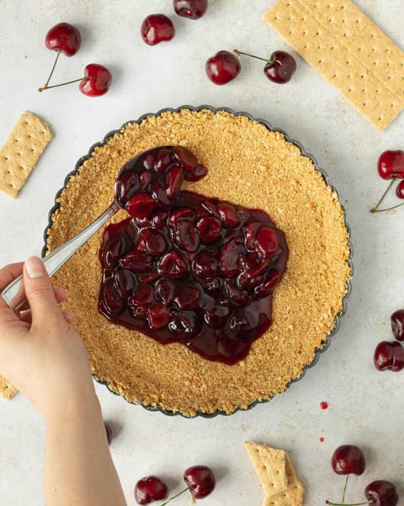 Pour the cherry sauce into the cool Graham cracker crust and spread evenly using a spatula.