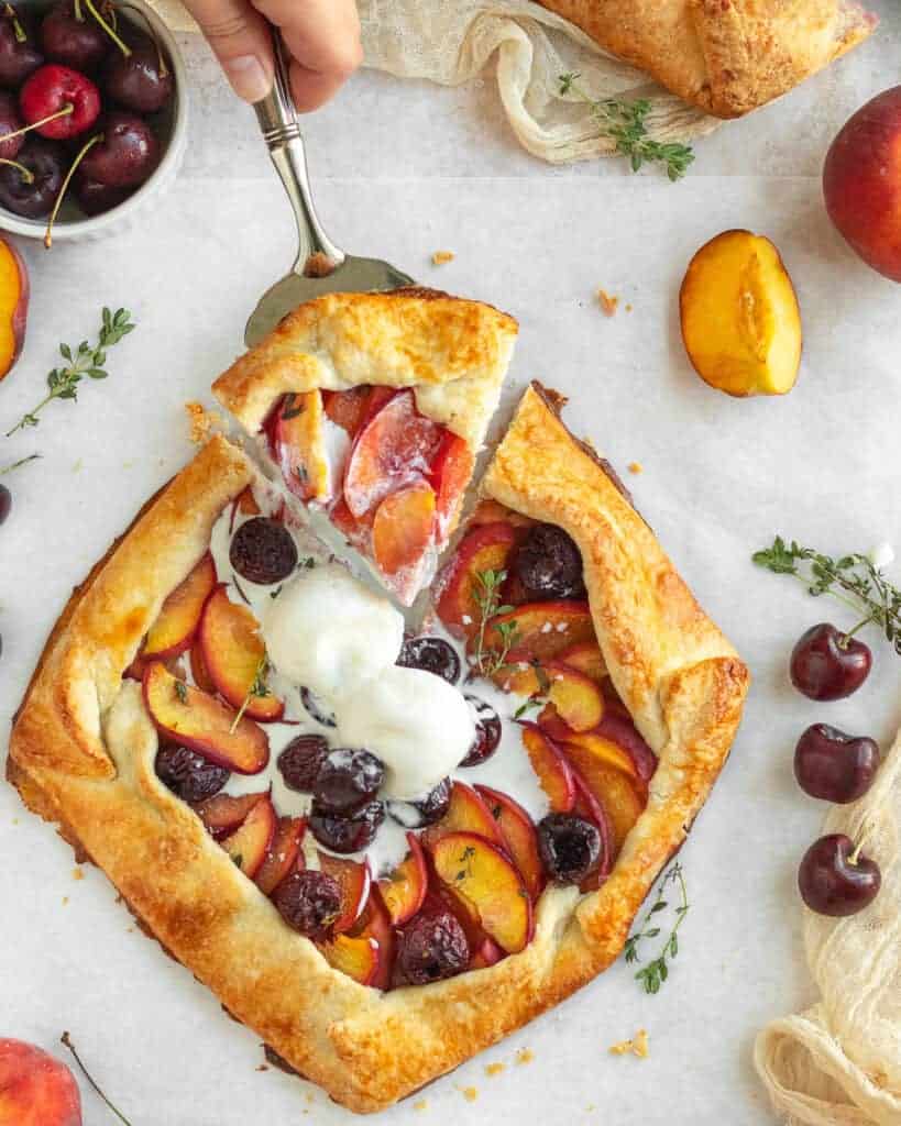 Overhead shot of Peach and Cherry galette topped with vanilla ice cream and sliced.