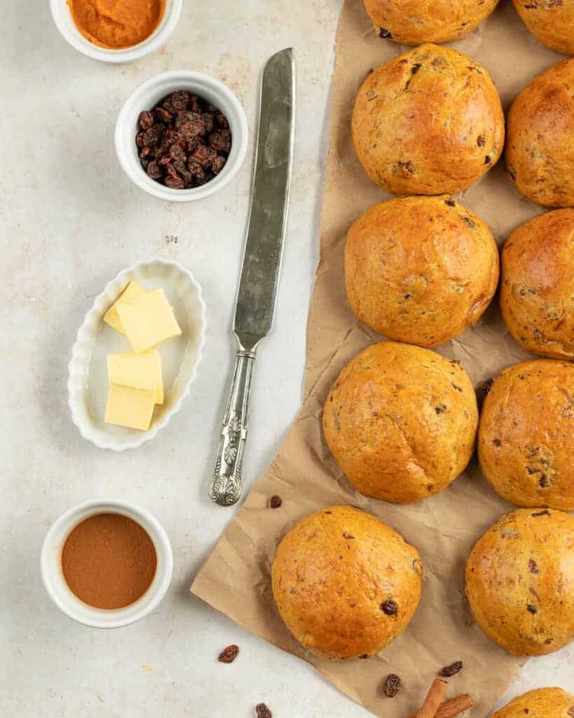 Overhead shot of raisin buns placed on craft paper served with sliced butter.