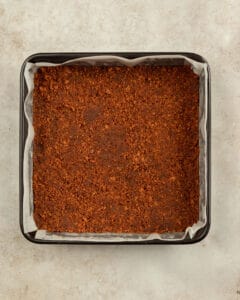 The gingersnap crust is spread in the baking pan.