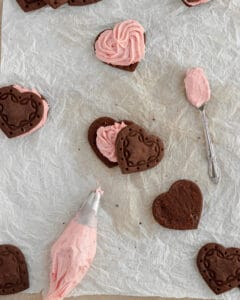 Photo of piping frosting to the heart shaped cookies.