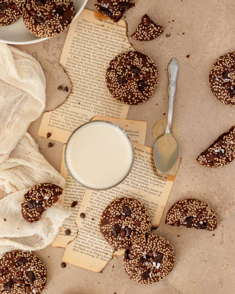 Overhead photo of double chocolate tahini cookies  spread on top of vintage book pages.