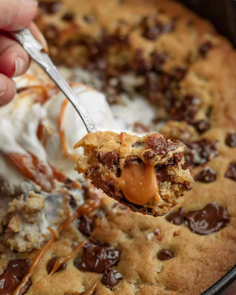 Closeup photo of sliced salted caramel skillet cookie with gooey caramel sauce.