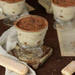 Photo of mini tiramisu trifles topped with cocoa powder and chocolate flakes.