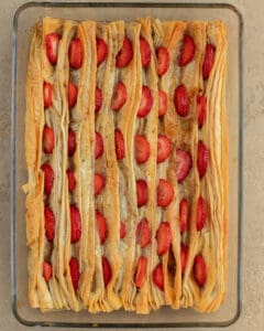 Photo of the custard filling and sliced strawberries placed on top of the baked phyllo layers before baking.